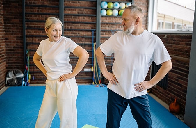Un signore e una signora anziani eseguono esercizi per ridurre i sintomi dell'artrite all'anca