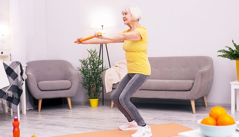 Una donna anziana fa squat come esercizio di fitness.