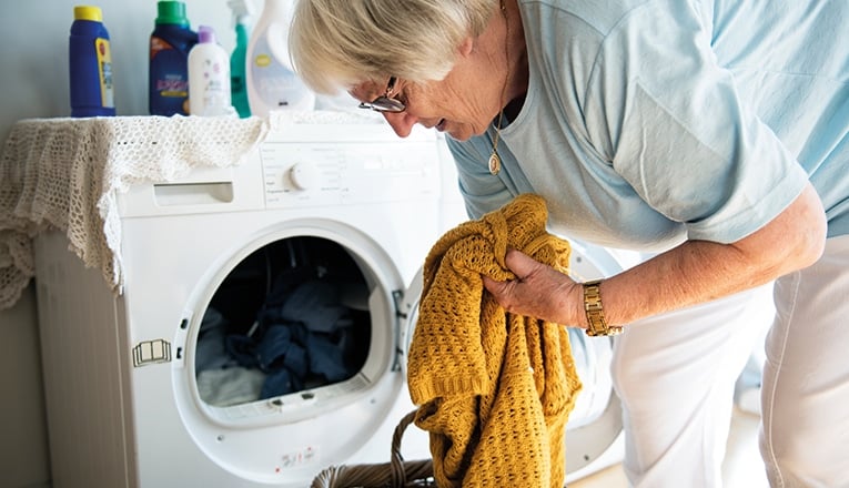 Signore con reumatismi continua a svolgere lavori domestici, come fare la lavatrice